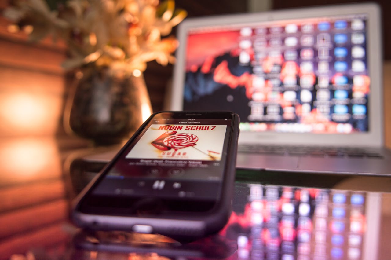 Modern workspace featuring a smartphone and laptop with vibrant lighting and reflections.